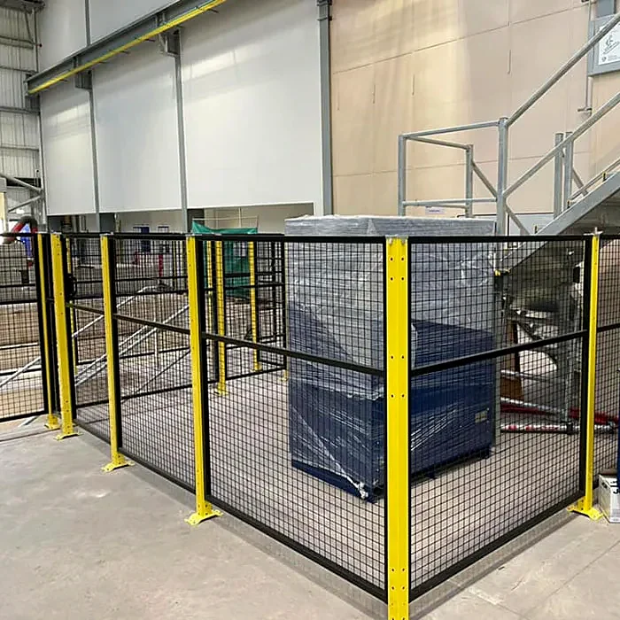 Mesh-panel enclosure with yellow posts around industrial equipment.